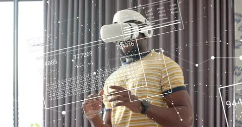 Reaching man wearing white VR headset and striped tee interacting with floating Stock Photos