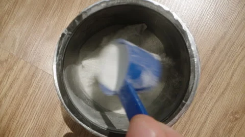 Reaching into the pre-workout powder jar with a blue scoop, preparing to measure Stock Footage 283791459