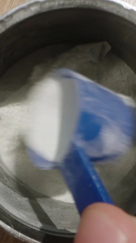 Reaching into the pre-workout powder jar with a blue scoop, preparing to measure Stock Footage 283791512