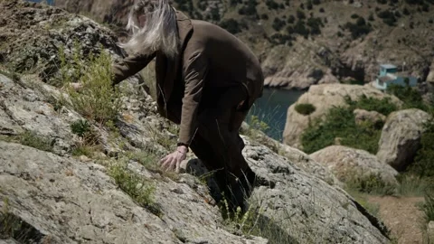 Reaching the top of a mountain in Crimea is a young man with long hair Stock Footage 136744007