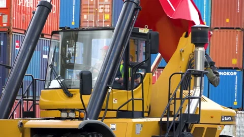 The reachstacker driver sits in the cab and operates the steering wheel. Stock Footage 148691746
