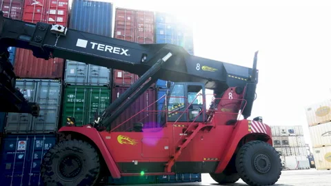 Reachstacker rides back against an open-air container warehouse. Stock Footage 148690454