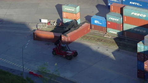 A reachstacker transports a large container through the terminal.  Stock Footage 166371721