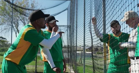 Reacting to coach gesture, diverse baseball team gathering inside batting cage, 動画素材 345070041
