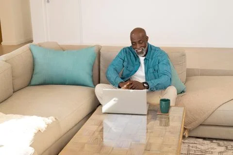 Reacting to left sunlight, man checking email on laptop at home with mug, Stock Photos