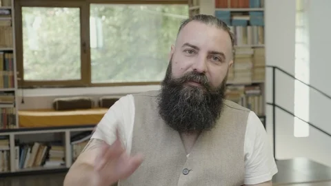 Reaction of a cool young man with beard looking at the camera and talking dur Stock Footage 90555437