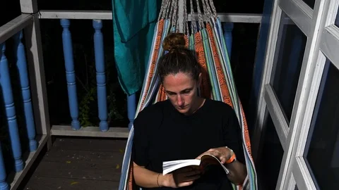 Read a book lying in the hammock on a summer night Stock Footage 126863169