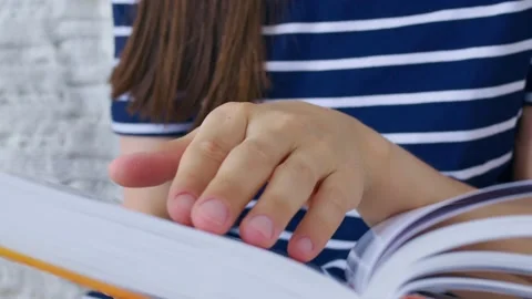 The reader carefully reads every line in the book. Reading a book develops 動画素材 157336670