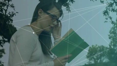 Reader reading green book under tree, looking down and animating node network Stock Footage 333648954