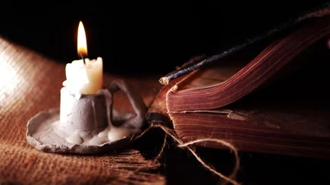 Reading an ancient worn book and candle on hessian sack Stock Footage 170304023