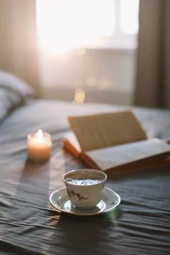 Reading and having breakfast in bed. Coffee cup and a book in bed. Cozy sunny Stock Photos