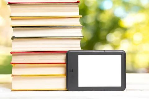 Reading and knowledge. E-book reader and a stack of books. The park is blurre Stock Photos