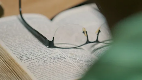 Reading Bible on Table with Glasses Stock Footage 128655659