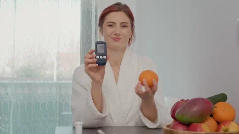 Reading blood sugar level and enjoying healthy fruits in the kitchen Stock Footage 346704390