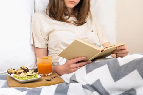 Reading book in bed and having breakfast.  Stock Photos