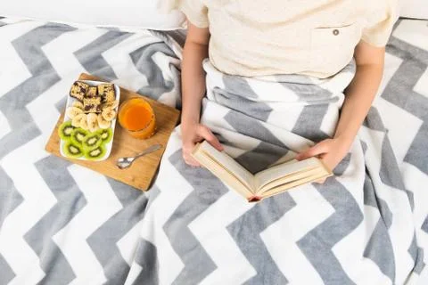 Reading book in bed and having breakfast, top view.  Stock Photos