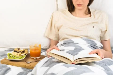 Reading book in bed and having breakfast.  Stock Photos