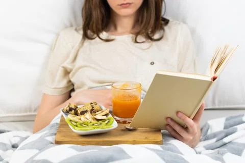Reading book in bed and having breakfast. Stock Photos