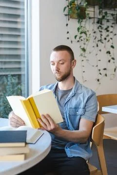Reading a book in a bright cafe while engaging in online education during t.. Photos