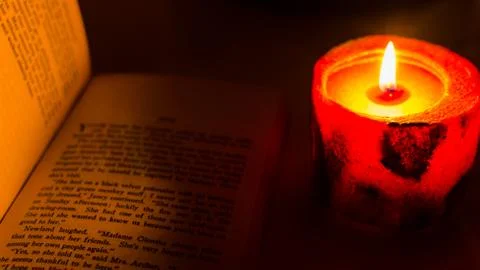 Reading a book by candlelight Stock Photos