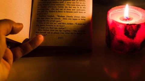 Reading a book by candlelight Stockfoto's