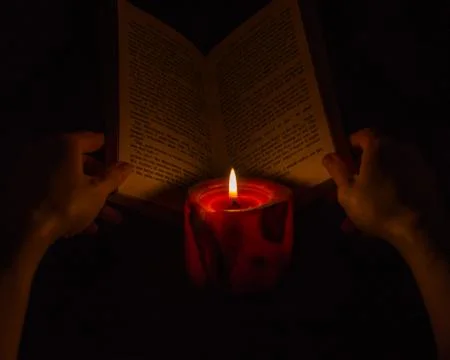 Reading a book by candlelight Stock Photos