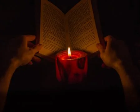 Reading a book by candlelight Stock Photos