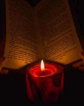 Reading a book by candlelight Stock Photos