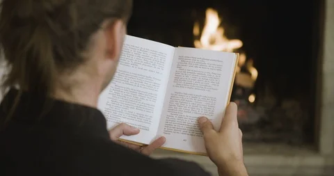 Reading a book in front of a fireplace Video stock 97934900