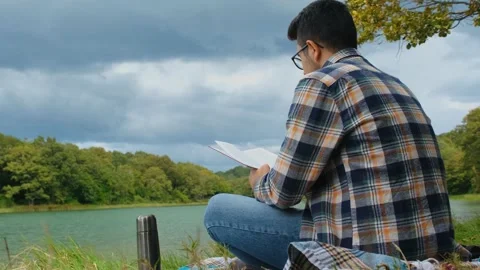Reading book by the lake in nature Stock Footage 219095474