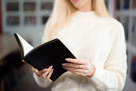 Reading book in library. Student in the library with a book in her hands. Stock Photos