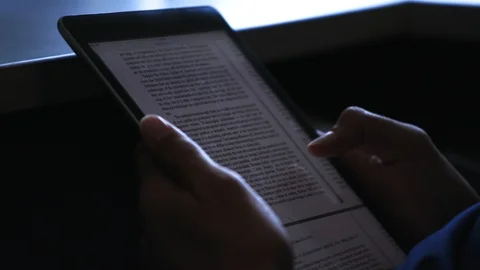 Reading a book on an tablet Stock Footage 103867211