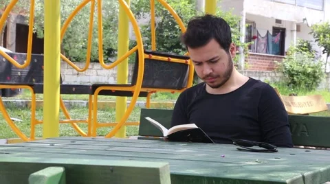 Reading book on wood table in park Stock Footage 65373248