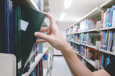Reading concept. Hand man selecting book from a bookshelf. Foto stock