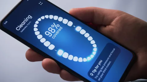 Reading dental care tips on a smart toothbrush app. Using a sonic electric Stock Footage 278047509