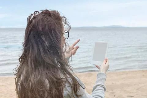 Reading a e-book on the beach. holding a e-book Stock Photos
