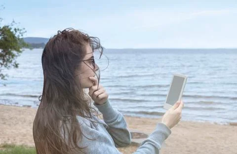 Reading a e-book on the beach. holding a e-book Stock Photos