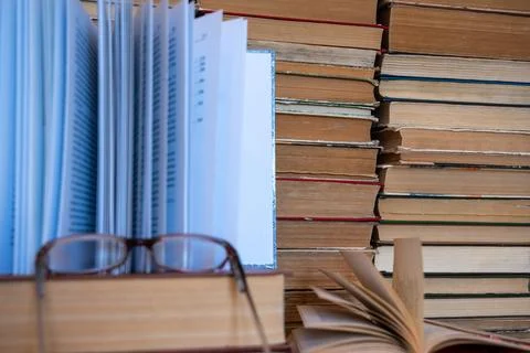 Reading glasses on book with stack of books in background. Stock Photos