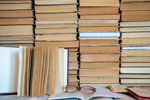 Reading glasses on book with stack of books in background. Stock Photos