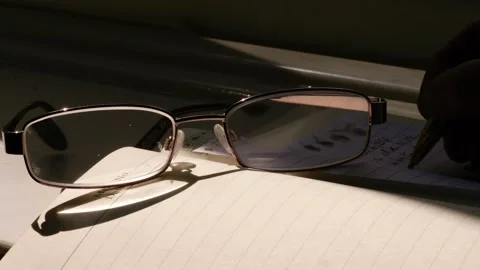 Reading glasses on notepad with hand making notes Stock Footage 278418859