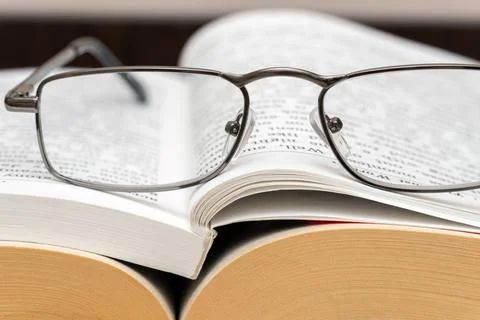 Reading glasses on a stack of books close up Stock Photos