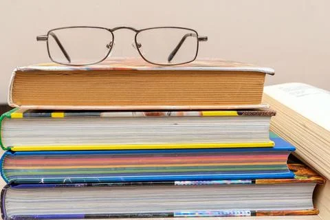 Reading glasses on a stack of books close up Stock Photos