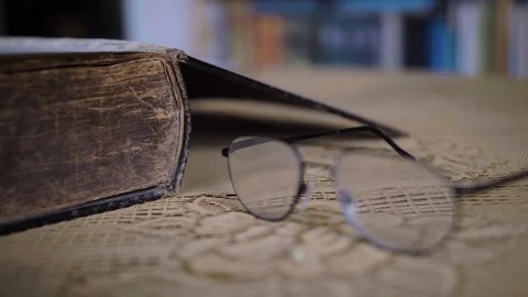 Reading Glasses On Table Next To Old Weathered Book On Table. Low Angle, Stock Footage 123499002