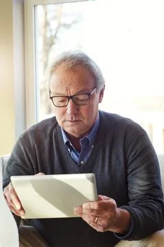 Reading, home and elderly man on tablet for communication, social media and.. Stock Photos