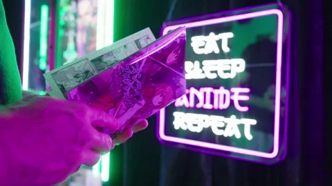 Reading Japanese manga comic beside Eat Sleep Anime Repeat futuristic neon sign Stock Footage 320008053