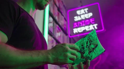 Reading Japanese manga comic under Eat Sleep Anime Repeat futuristic neon sign Stock Footage 320008681