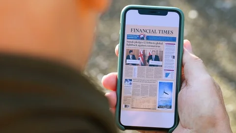 Reading latest Financial Times on the smartphone screen with coronavirus news Stock Footage
