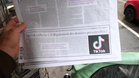 Reading le monde des media newspaper reading article about the privacy of TikTok Stock Footage 145033278