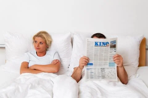 Reading a newspaper in bed Stock Photos