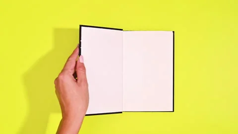 Reading the Past: Woman's Hands Open Vintage Black Book to Blank Page Stock Footage 254799110